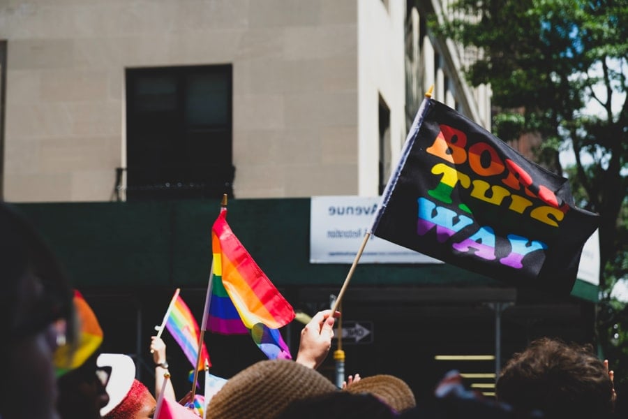 Tops of heads visible at a Pride march with a flag that says: 