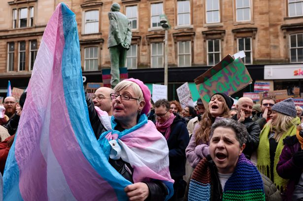 Trans rights activists at a protest, looking colourful and waving trans flags