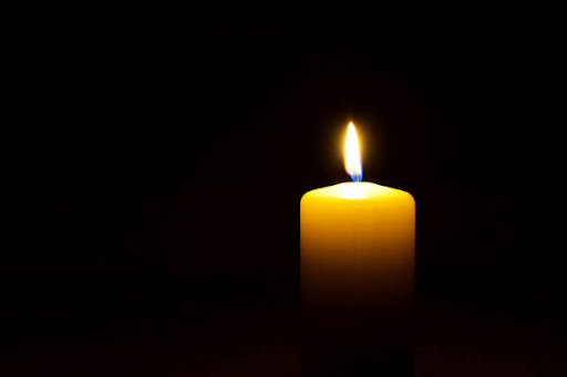 A candle glowing warmly in a dark background